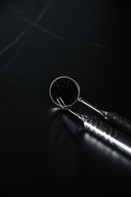 Detailed shot of dental tools on a dark surface, highlighting their metallic texture.