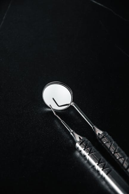 Dental mirror and tool on a black background, emphasizing healthcare and dental themes.
